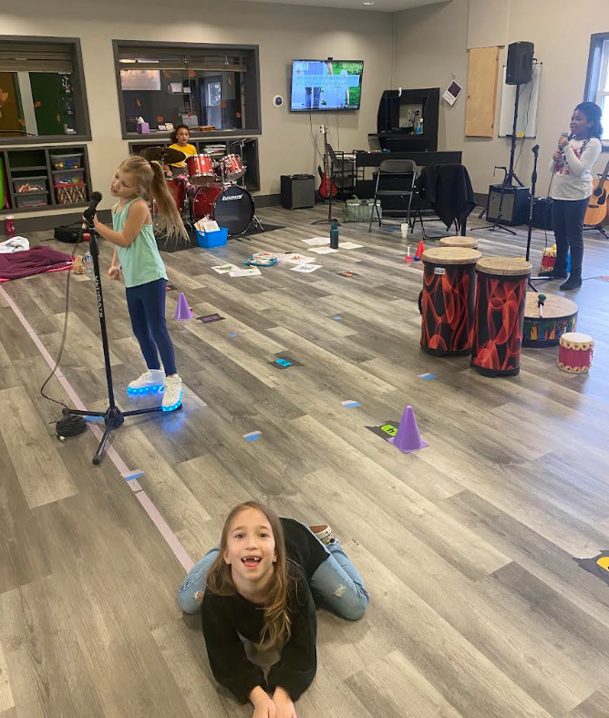 Miss Olivia teaching children in her music lesson room with drums and equipment