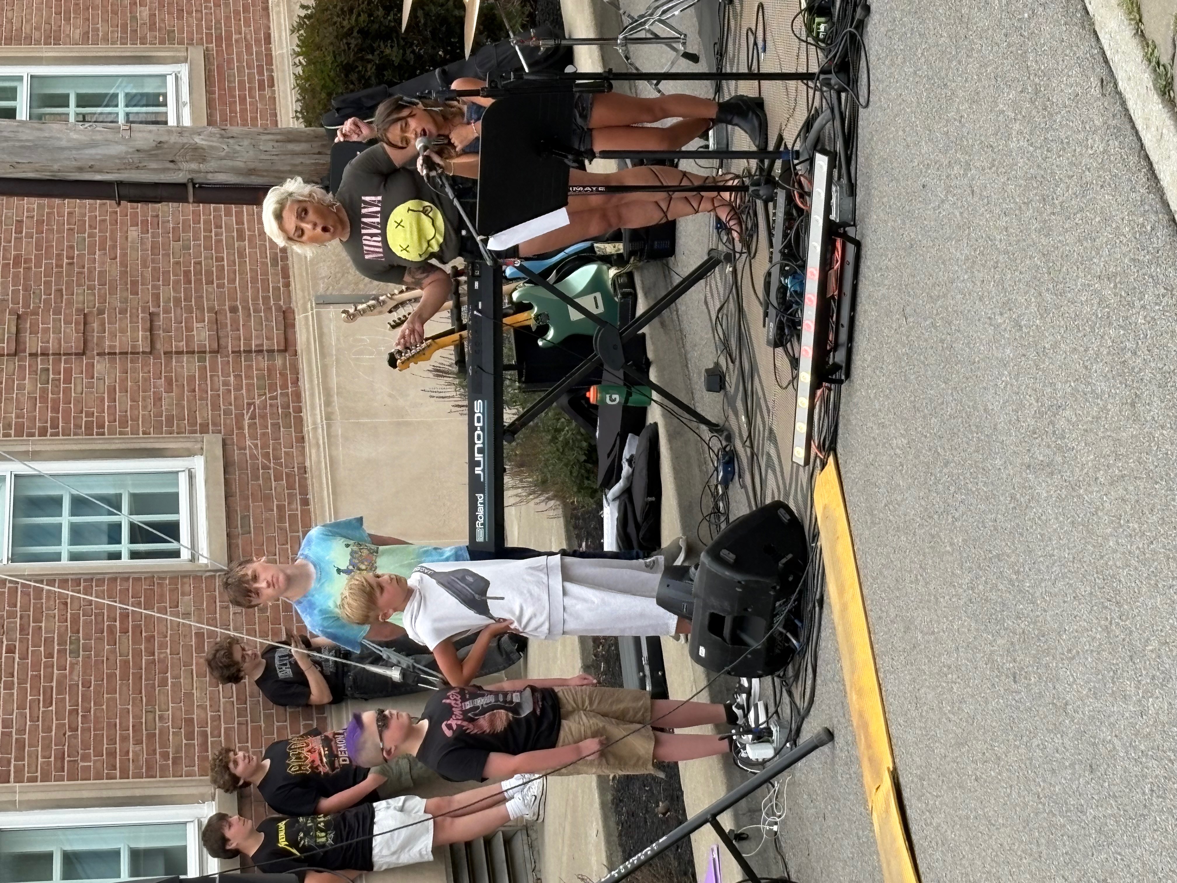 Miss Olivia performing outdoors with students and keyboard setup