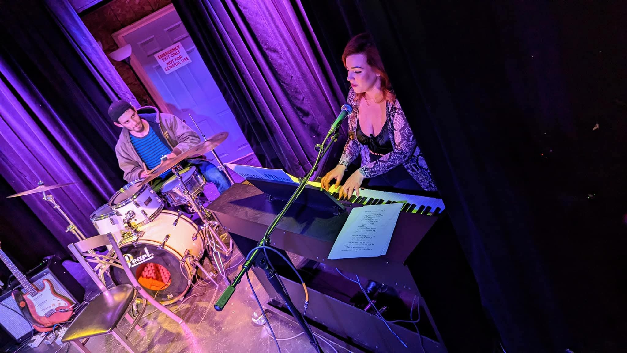 Miss Olivia performing on stage with purple lighting and keyboard